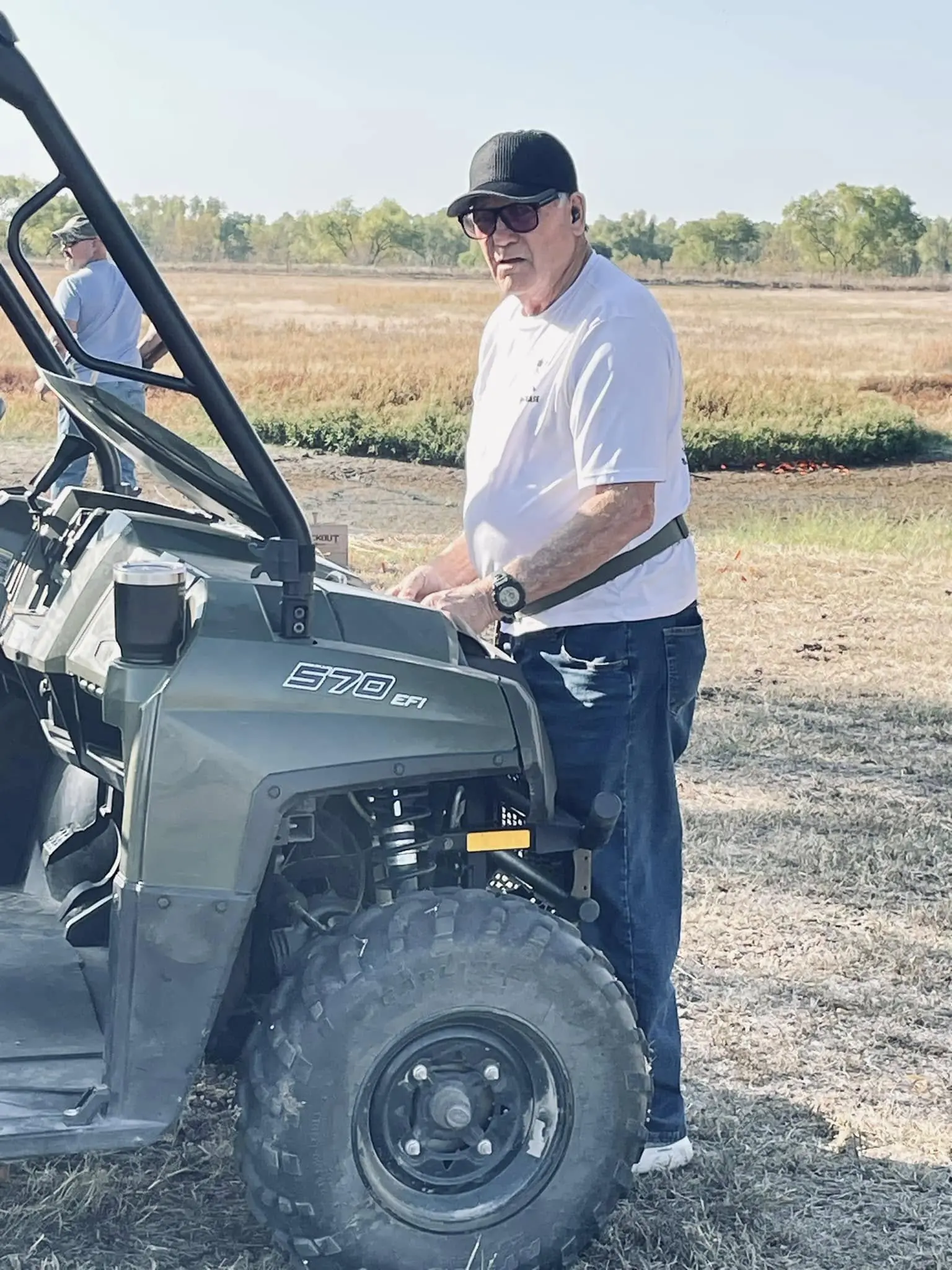 A man standing next to an atv in the dirt.