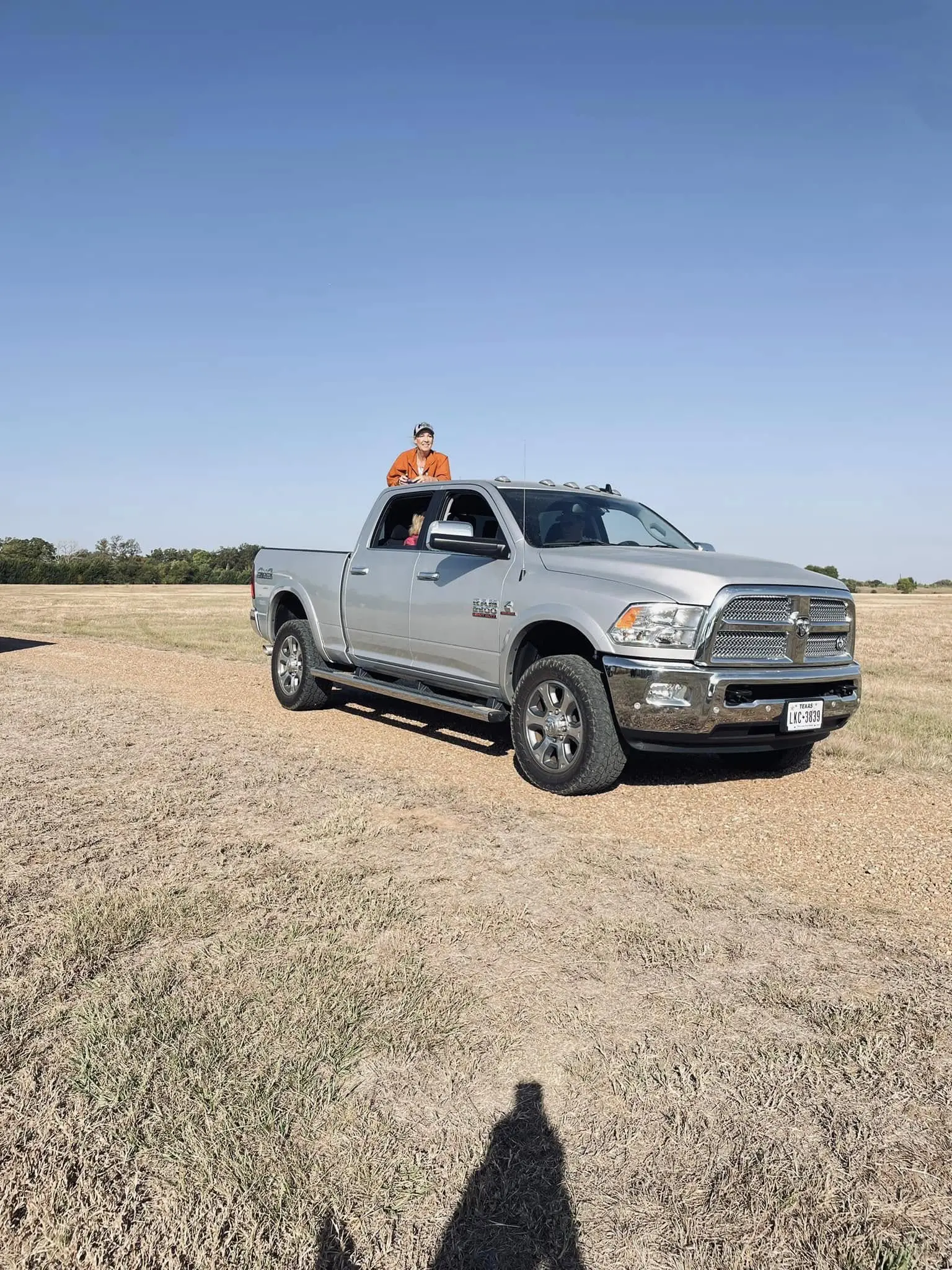 A man standing on the hood of a silver truck.