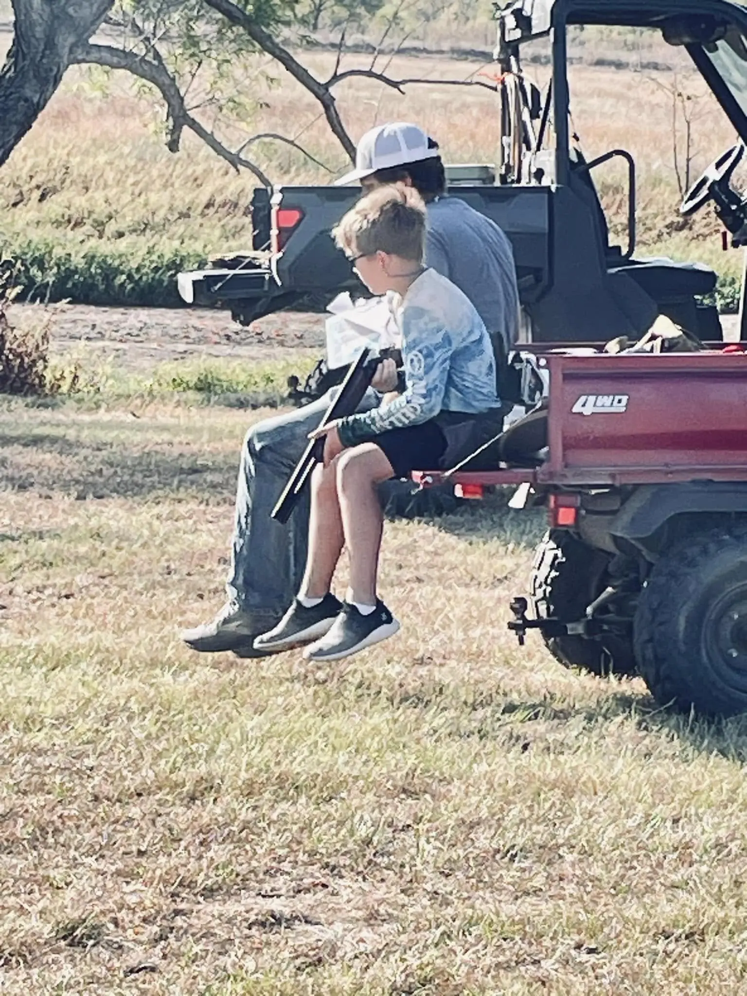 A man sitting on the back of a red utility vehicle.