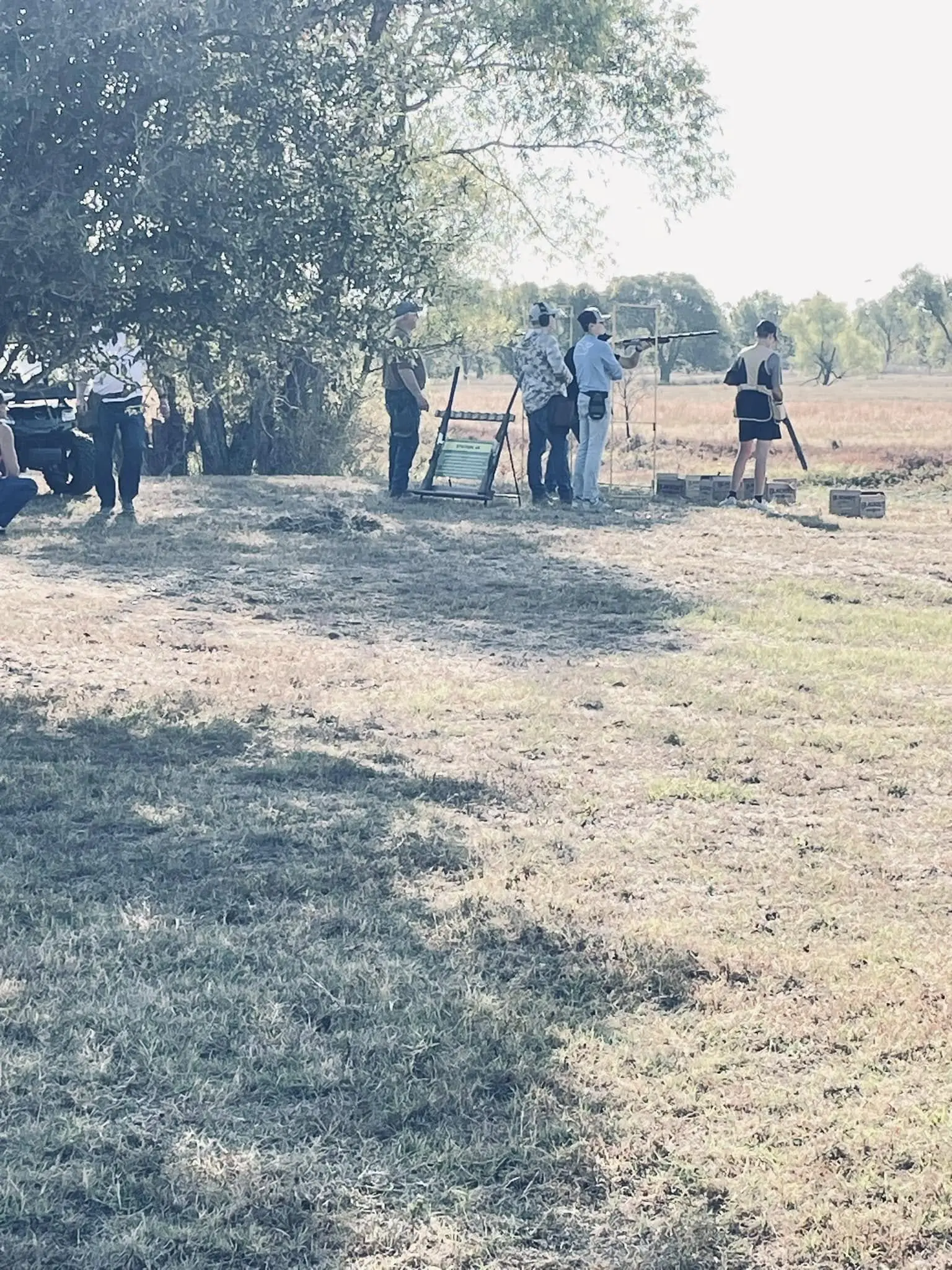 A group of people standing on top of a dry grass field.