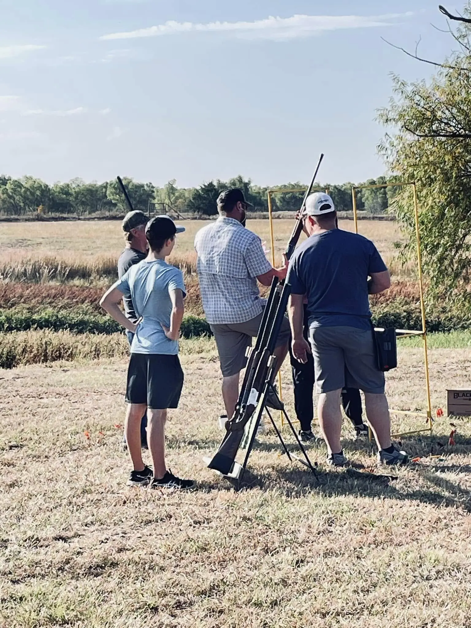 A group of people standing around in the grass.