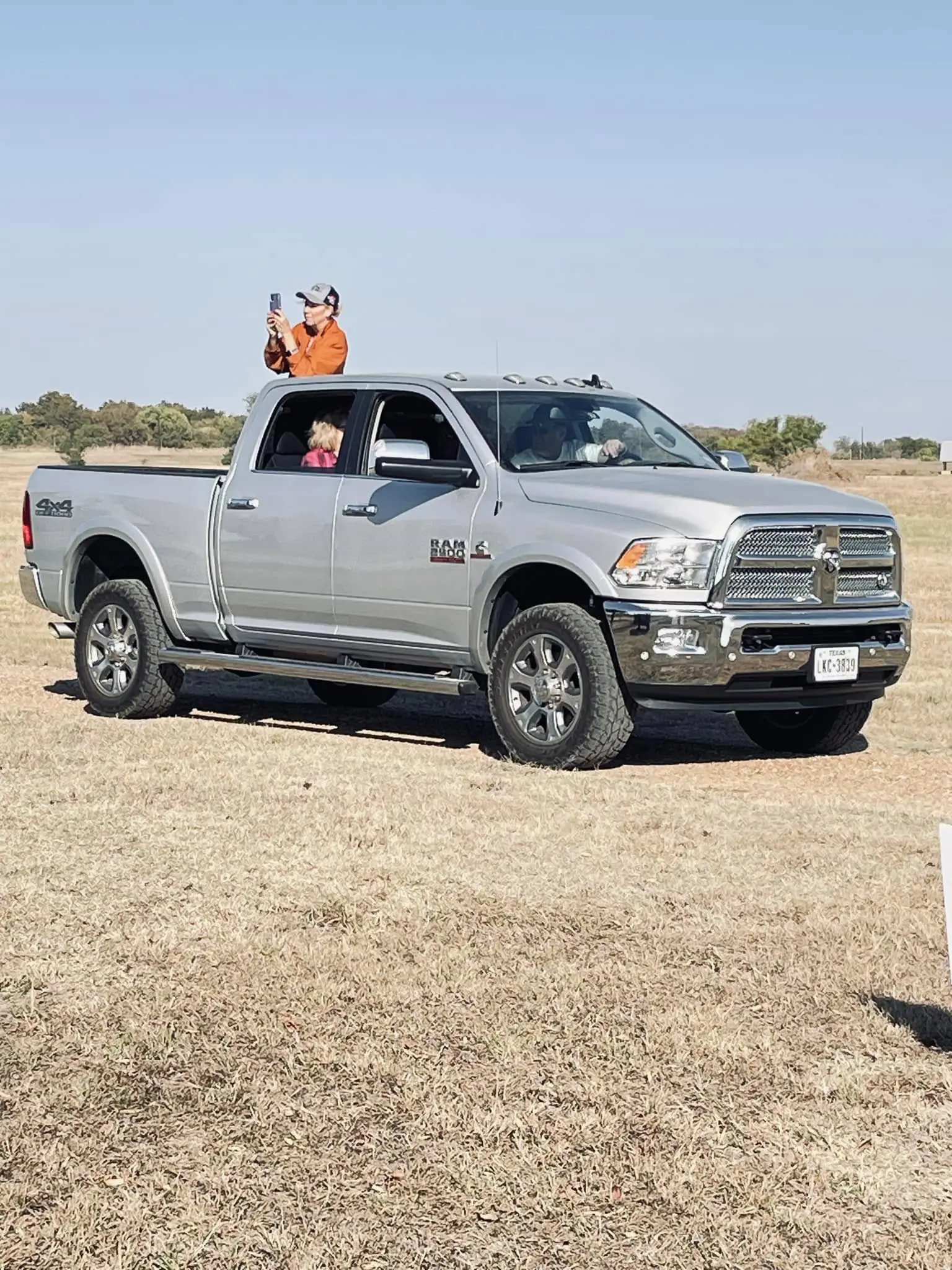 A silver truck with two people in the back of it.