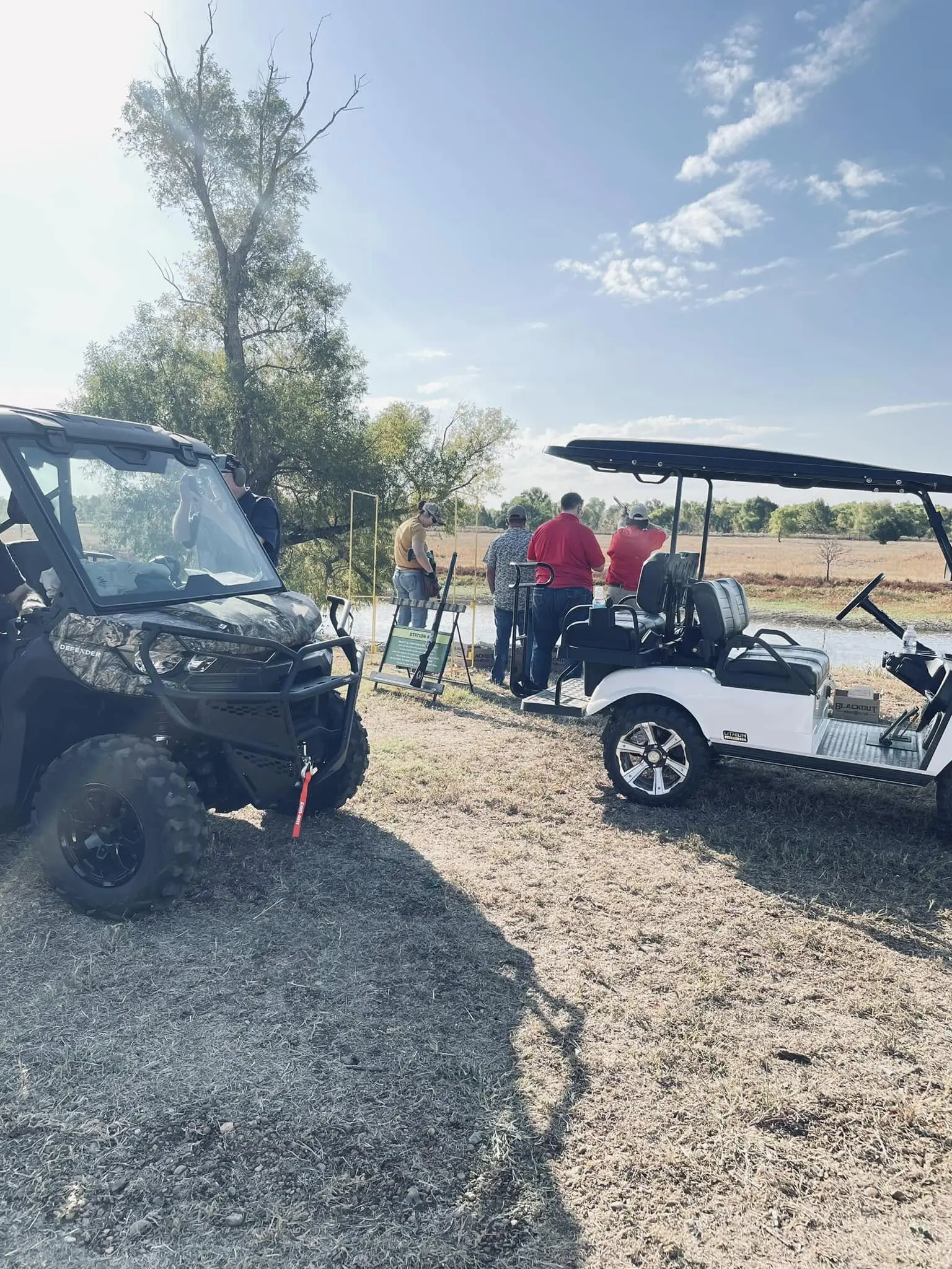 A group of people standing around golf carts.