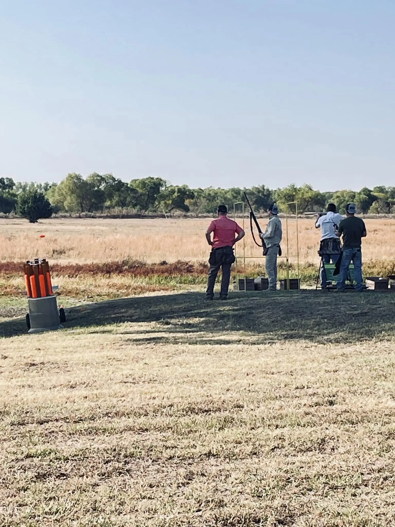 A group of people standing around in the grass.