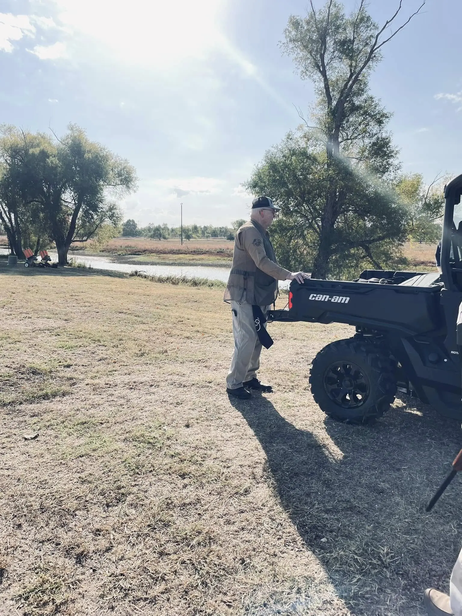 A man standing next to an atv in the grass.