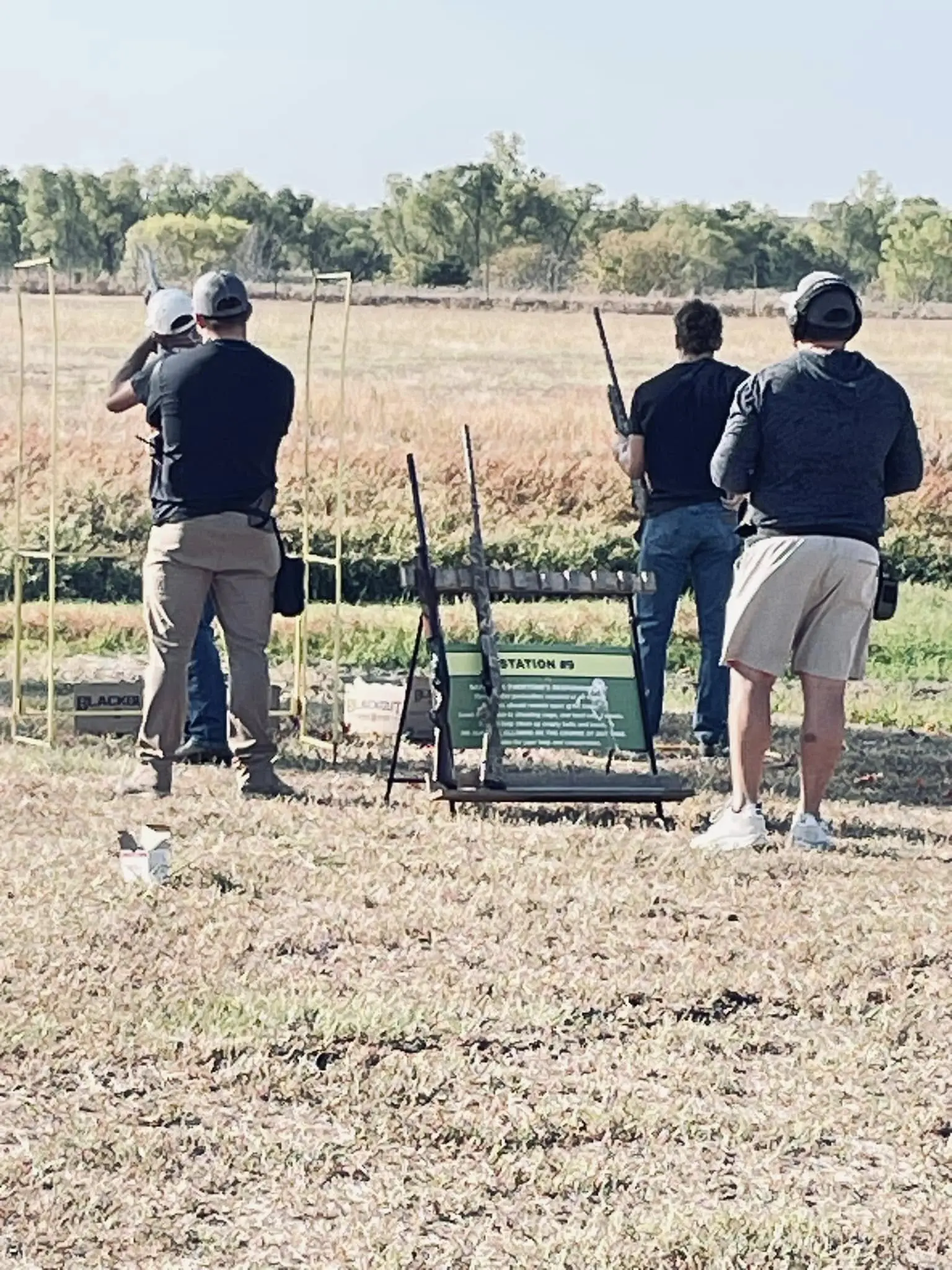 A group of people standing in the grass with guns.