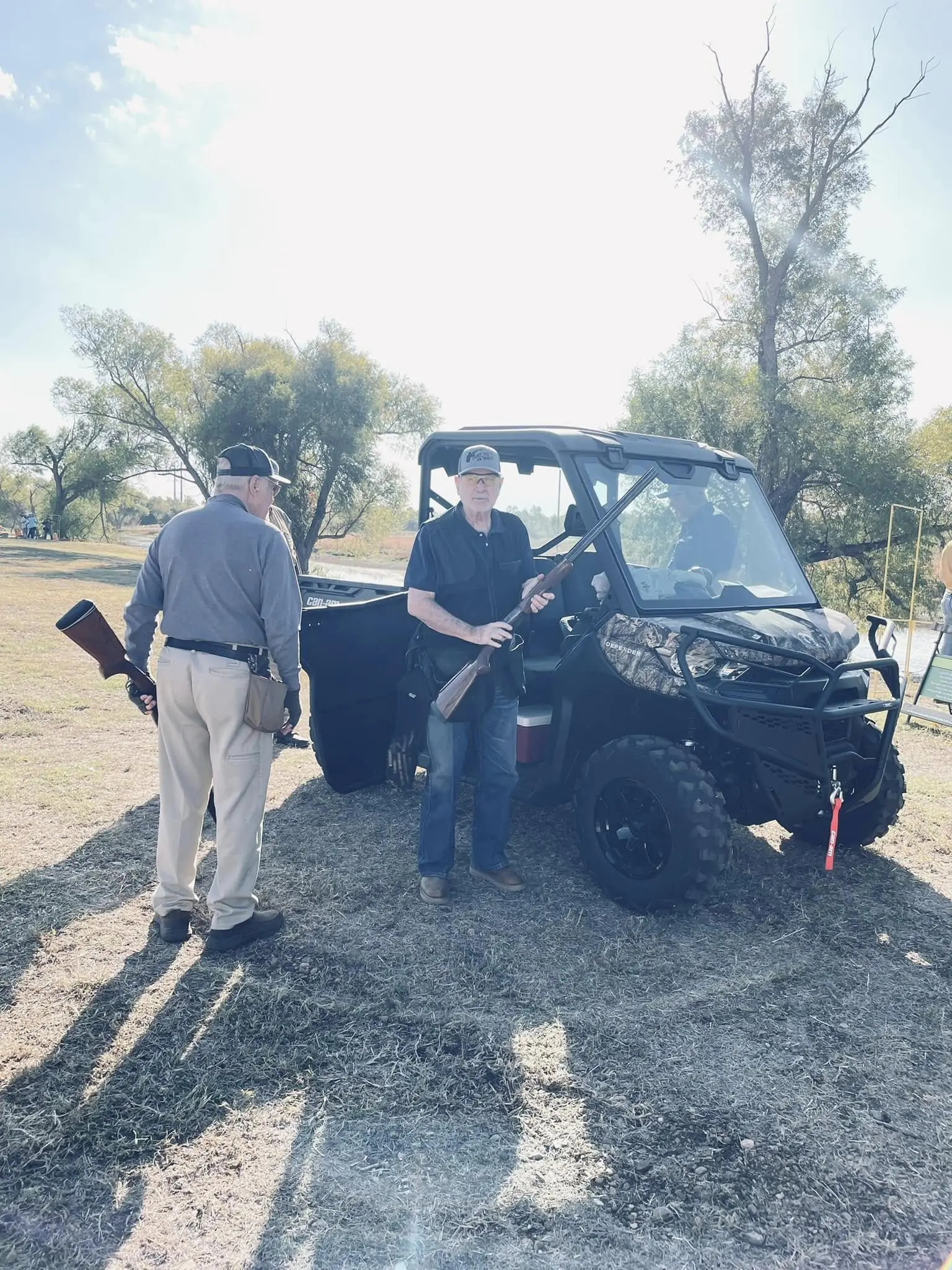 Two men standing next to a black utility vehicle.