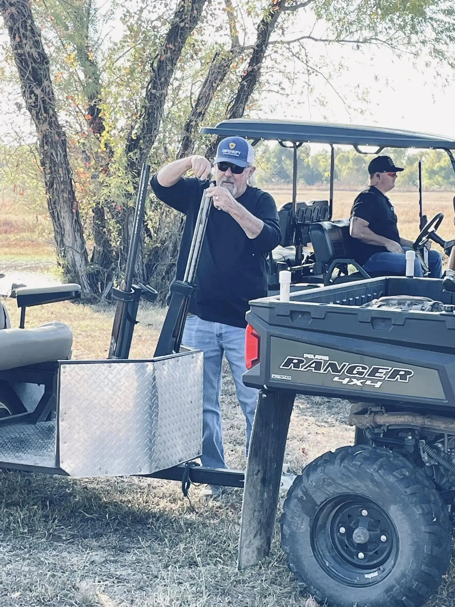 A man standing next to a trailer with two men.