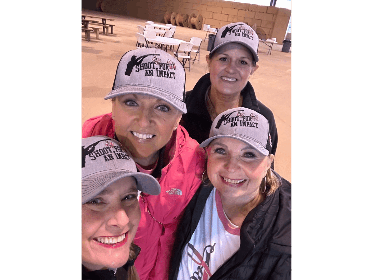 Four women wearing hats and smiling for a picture.